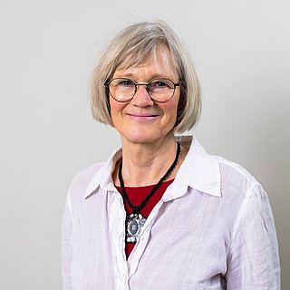 Frau in stehedener Haltung blickt freundlich in die Kamera