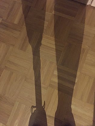 Schatten von zwei Beinen, wobei eines davon eine Holzprothese ist.