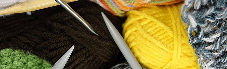 Bunte verschiedenfarbige Wollknäuel mit verschiedenen Strick und Häkelnadeln